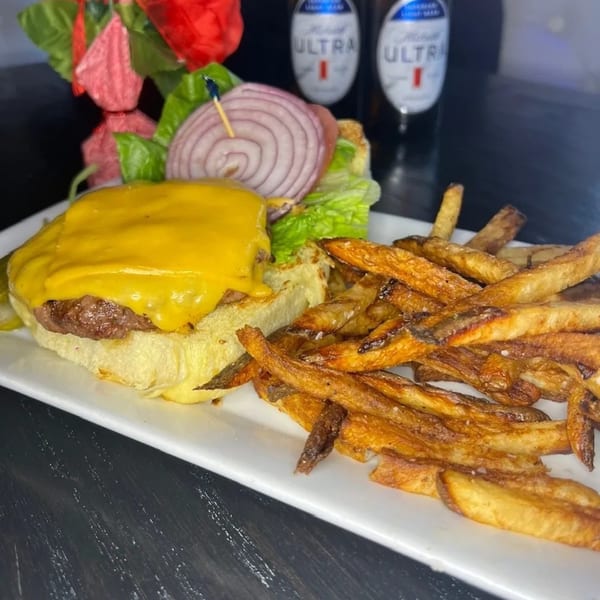 A Nunzi's American Bistro cheeseburger with red onion, lettuce, and a side of crispy fries.